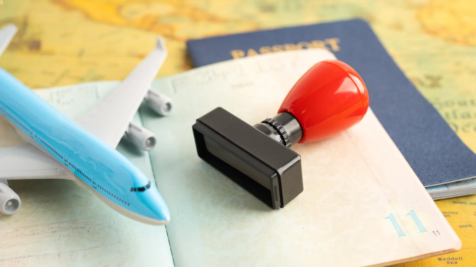 Pasaporte, sello de visado y avión en miniatura sobre un mapa del mundo