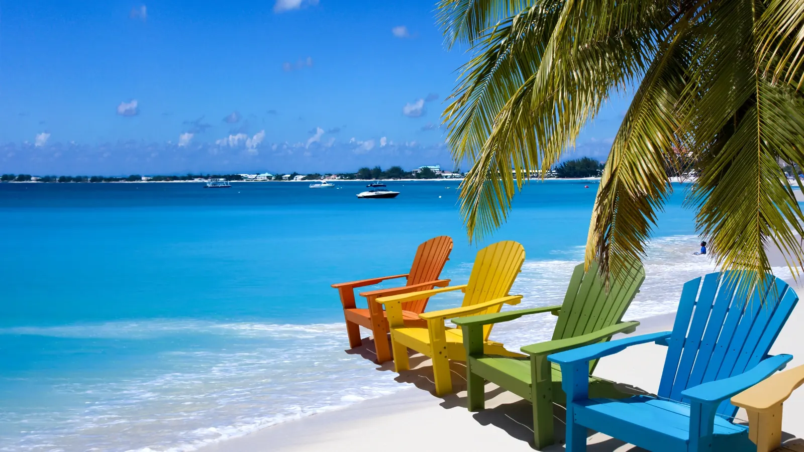 Sillas de playa de colores bajo las palmeras junto a un mar turquesa