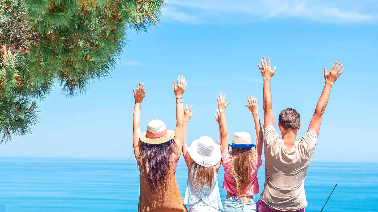 Famille bras levés face à la mer, en voyage organisé au départ du Maroc