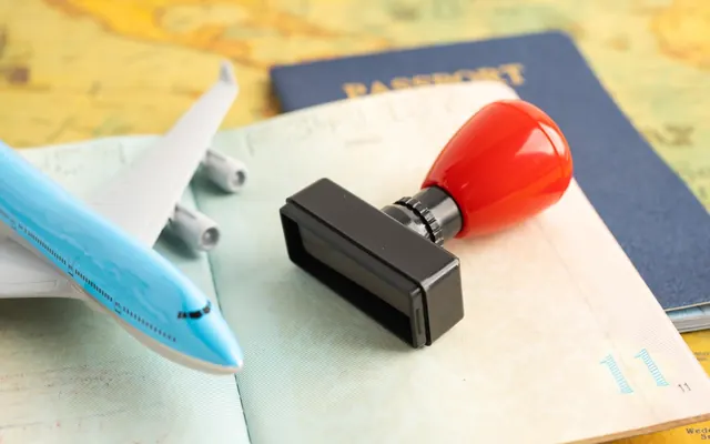 Pasaporte, sello de visado y avión en miniatura sobre un mapa del mundo