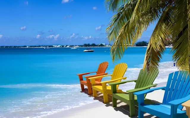 Chaises de plage colorées sous les palmiers au bord d'une mer turquoise